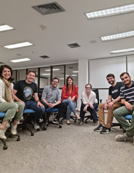 Pessoas reunidas analisando uma mesa com post it durante uma dinâmica de grupo.